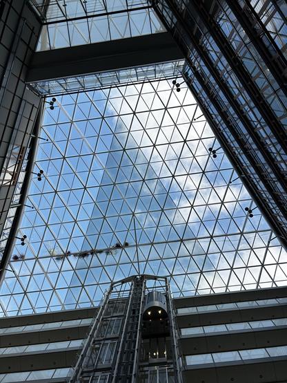 A photo of the glass ceiling at the European Investment Bank. Triangular window panels give a view of a blue sky with a few white clouds